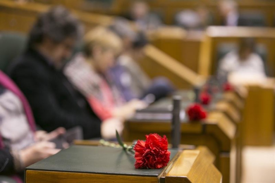 Los parlamentarios de EH Bildu muestran cinco claveles rojos en memoria de los asesinados. EFE