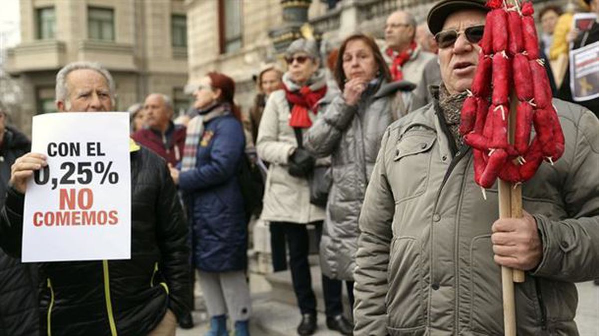Pensionistas protestan con carteles y portan una ristra de chorizos, frente al Consistorio bilbaino.