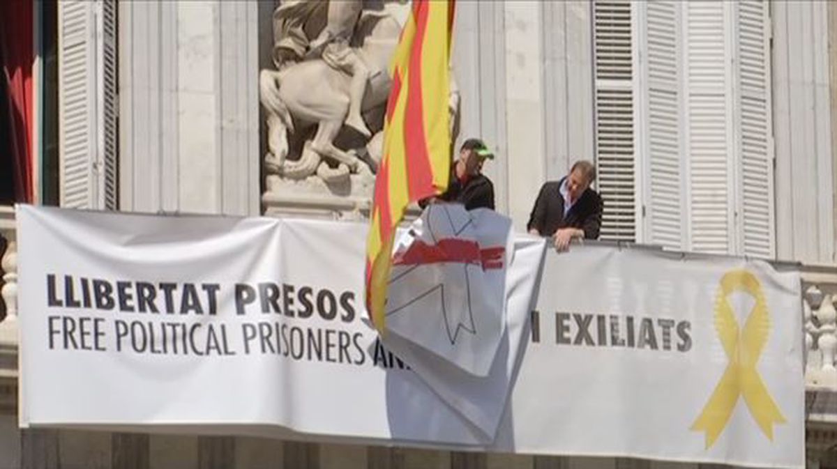 Dos trabajadores retiran las pancartas del Palau.