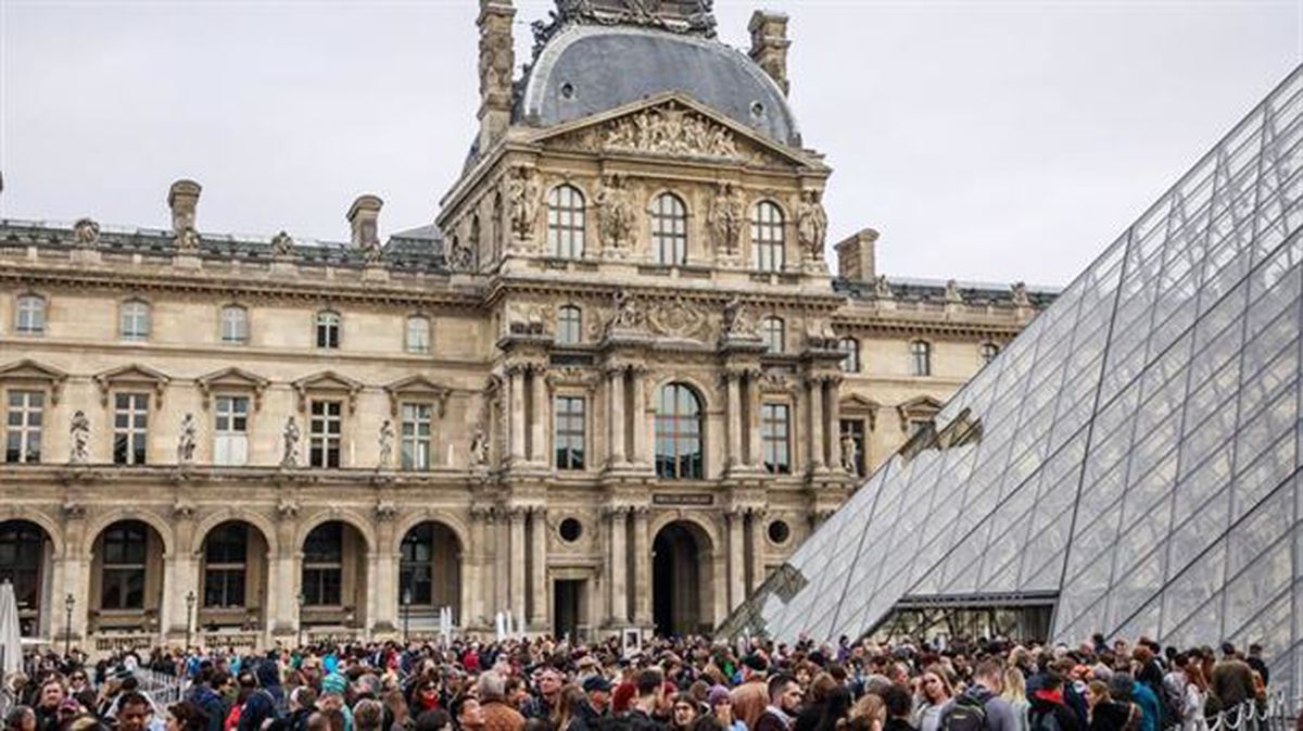 Los visitantes hacen cola frente a la Pirámide del Museo del Louvre, en Francia. Foto: EFE