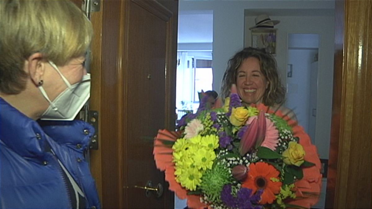 Una madre recibe un ramo de flores en la puerta de su  casa.