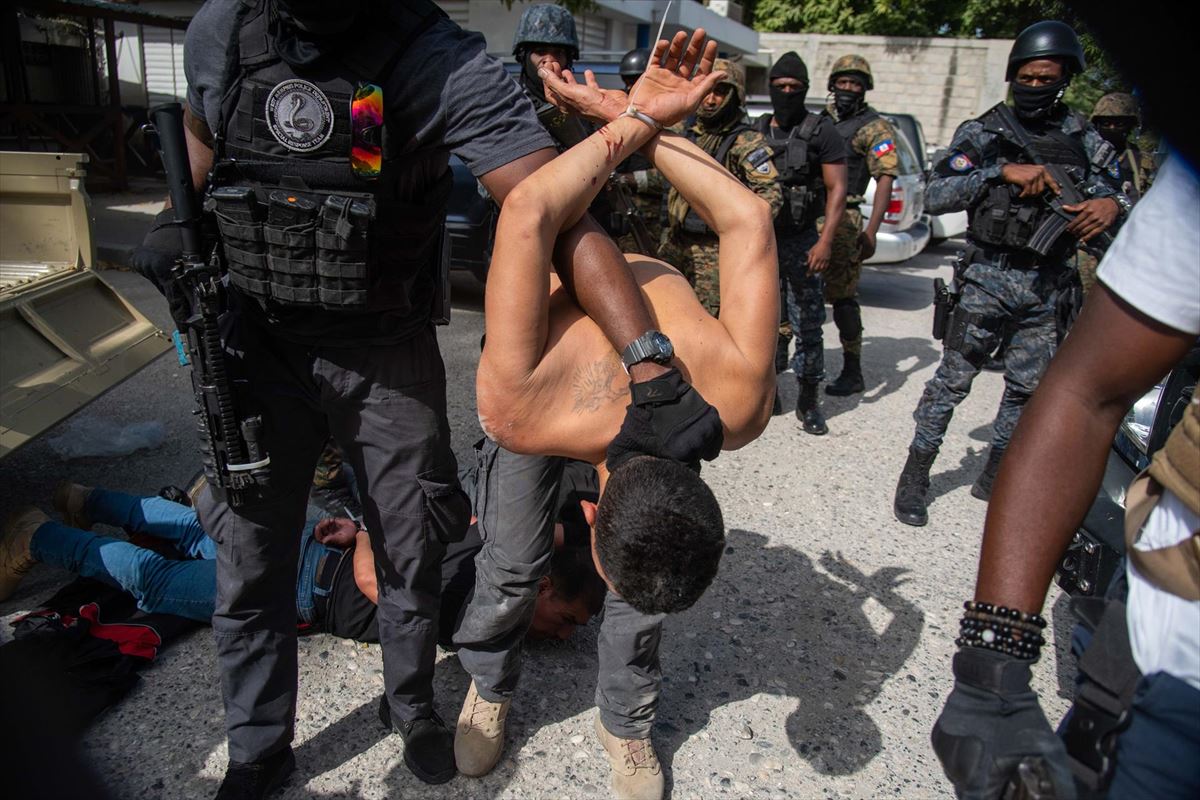 Poliziak susmagarri talde bat zaintzen ari da Haitiko presidentearen hilketagatik.