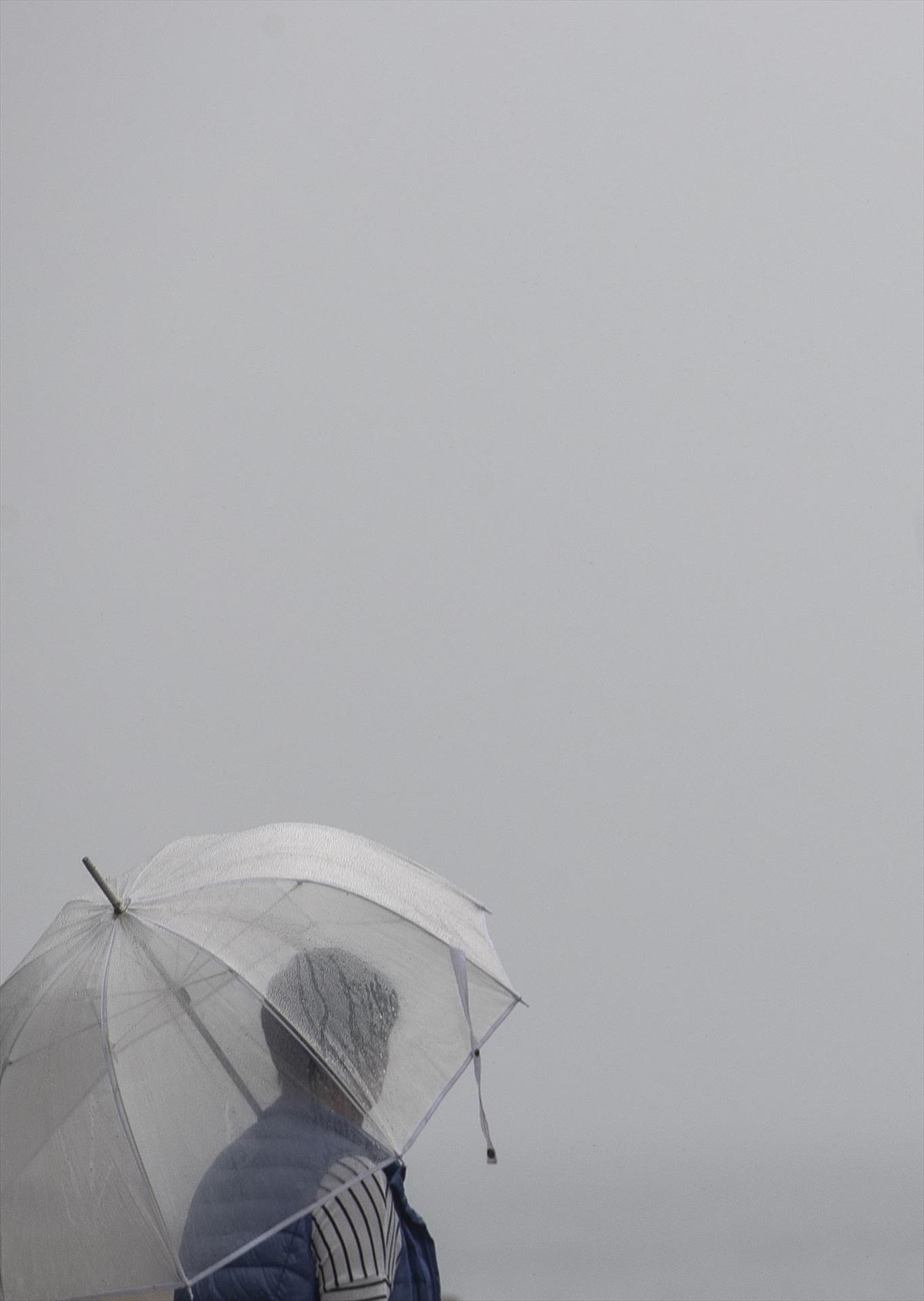 Una mujer, bajo el paraguas, en Donostia. Foto: EFE