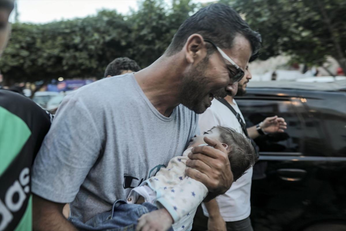 Un hombre lleva al hospital a un bebé herido, en Gaza. EFE. 