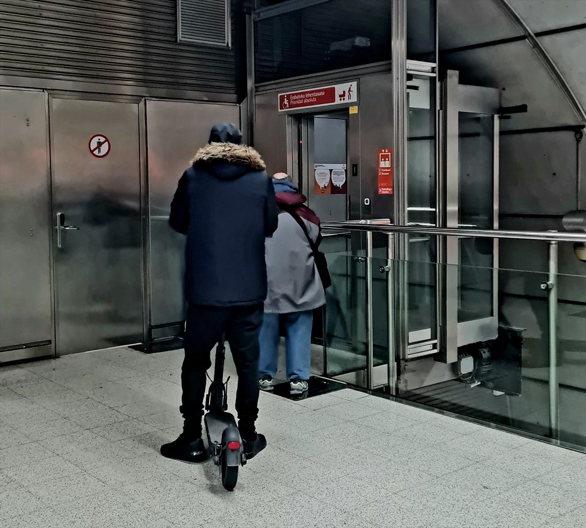 Metro Bilbaoko erabiltzaile bat patinete batekin igogailuan sartzeko zain.