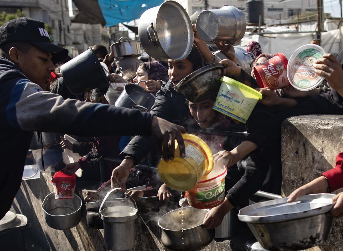 Palestinos desplazados sostienen cazuelas vacías para recibir ayuda al sur de la Franja de Gaza.