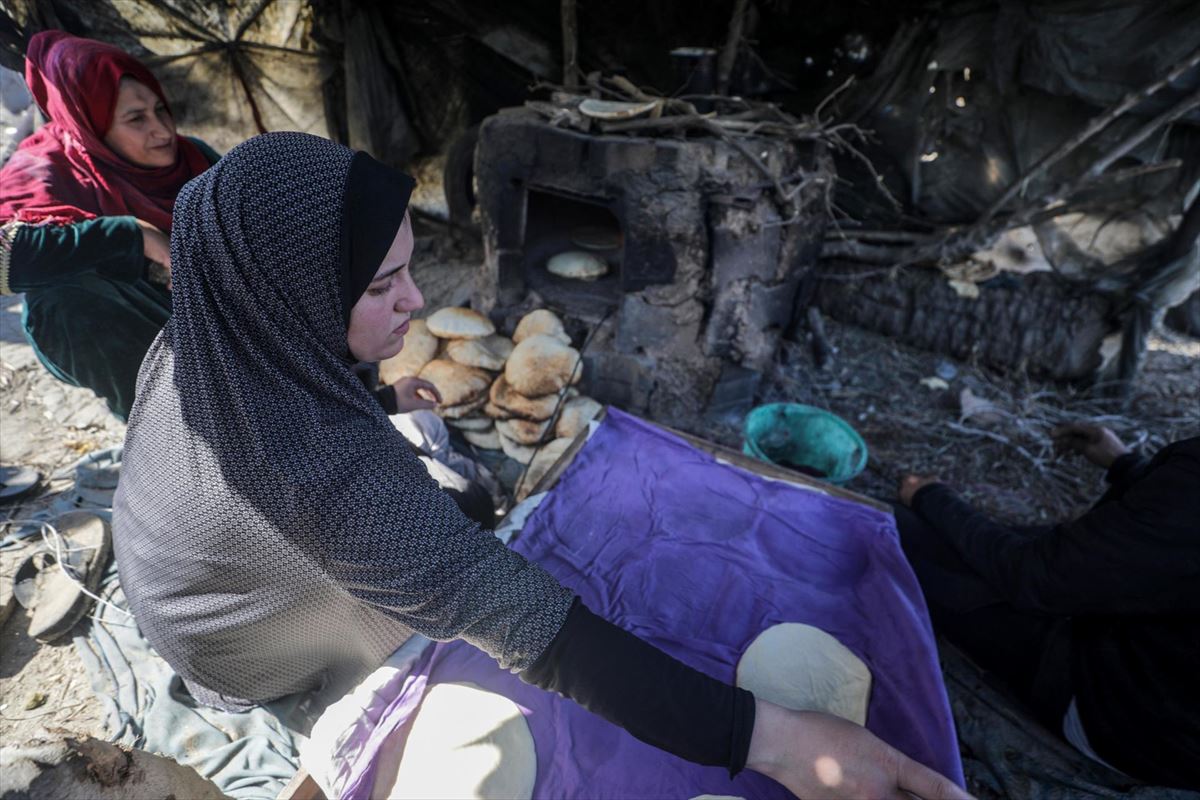 Gazako emakumeak hondakin artean inprobisatutako labeetan ogia egiten. EFE. 