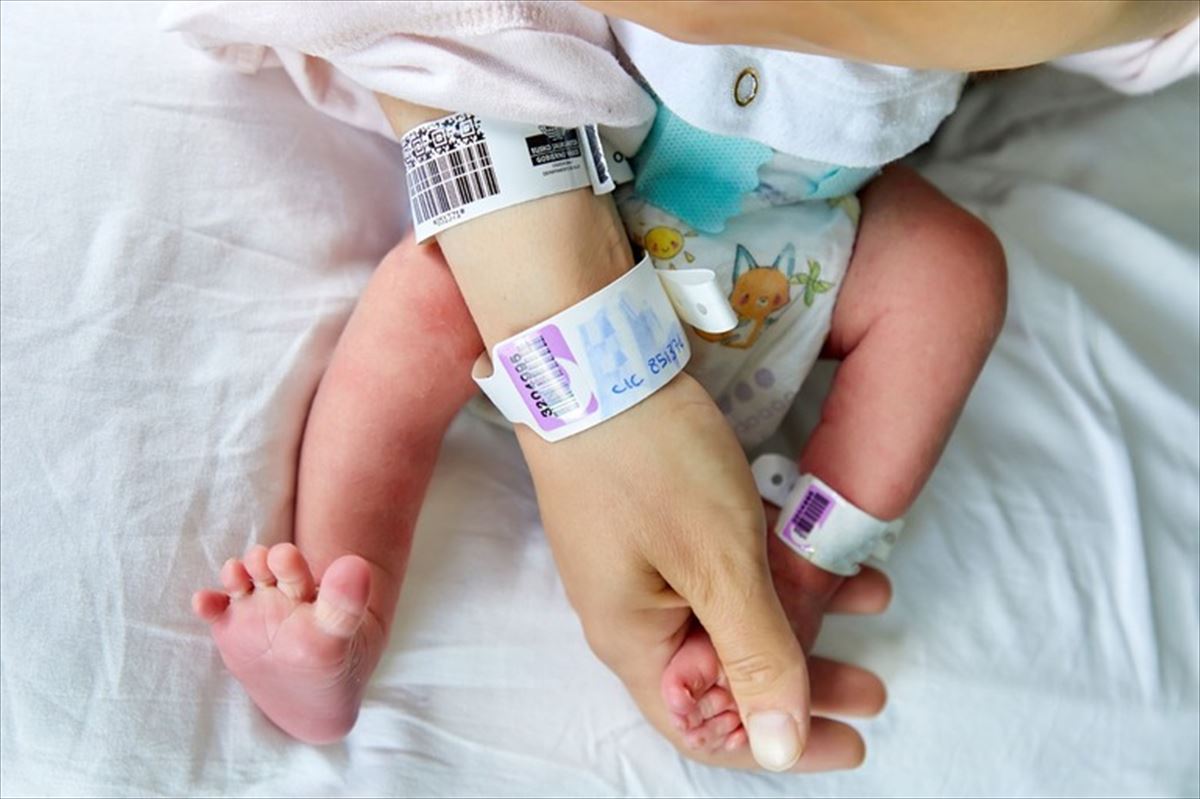 Una mujer agarra el pie de un recién nacido. 